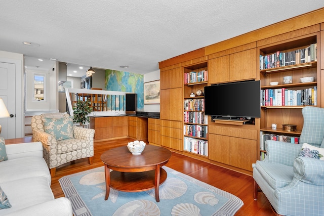 living room featuring built in shelves, a textured ceiling, and dark hardwood / wood-style floors