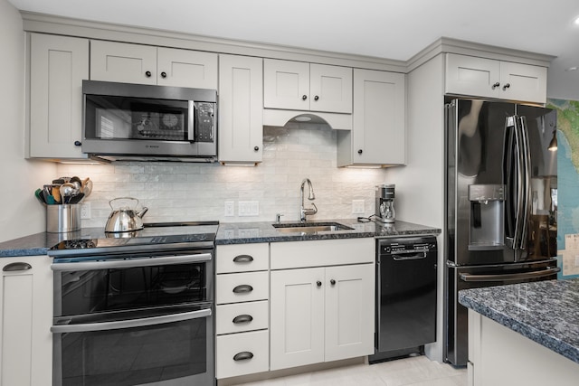 kitchen with sink, black appliances, tasteful backsplash, and dark stone counters