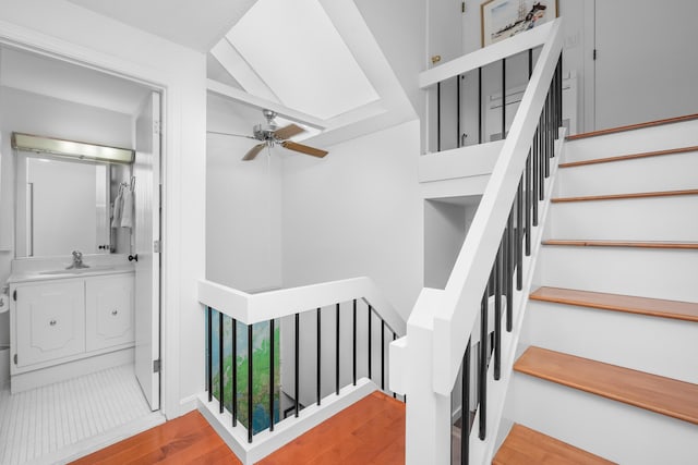 stairway with sink, ceiling fan, and hardwood / wood-style floors