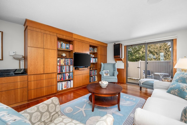 living room with built in shelves and hardwood / wood-style floors