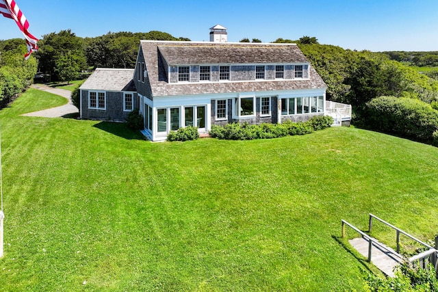 rear view of property with roof with shingles and a yard