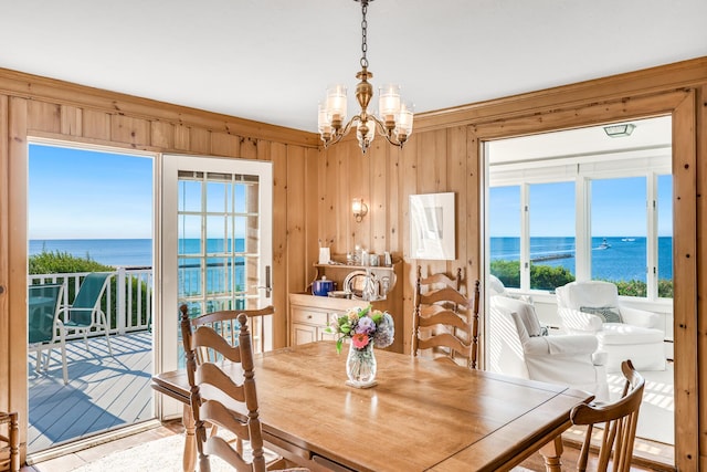 dining area with a water view, wooden walls, and a chandelier