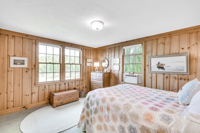 bedroom with cooling unit, multiple windows, wooden walls, and carpet