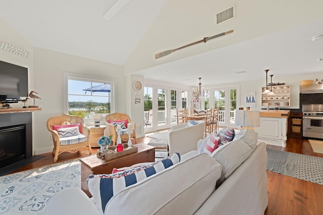 63 Briar Spring Rd, Orleans, MA 02653 - living area with french doors, wood finished floors, a fireplace with flush hearth, high vaulted ceiling, and a chandelier