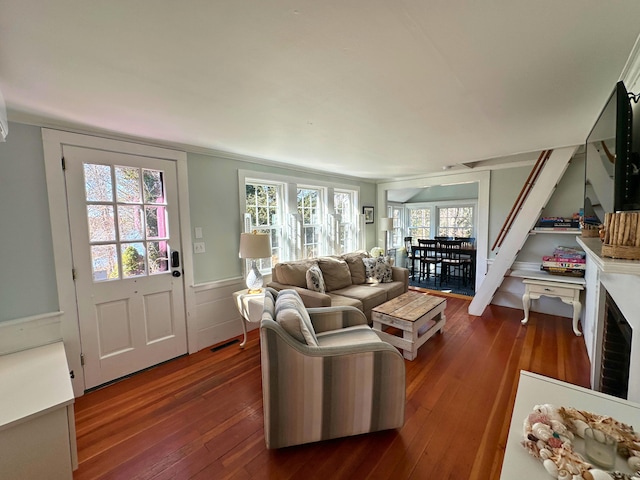 living area with wood-type flooring, visible vents, and wainscoting