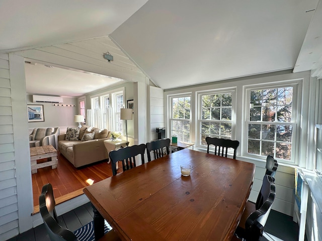 dining room with lofted ceiling, a wall mounted air conditioner, and wood finished floors