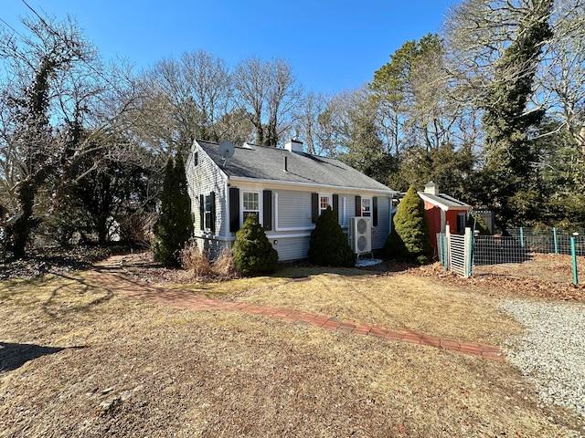 view of front facade featuring a shingled roof, a chimney, and fence