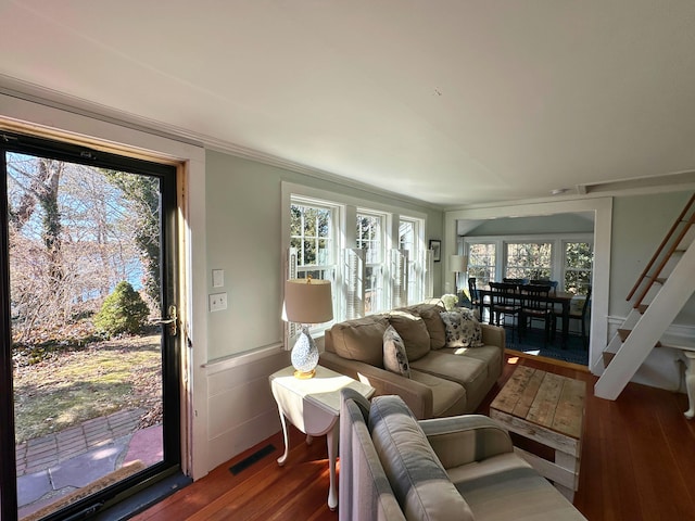 living room with wood finished floors, visible vents, and crown molding