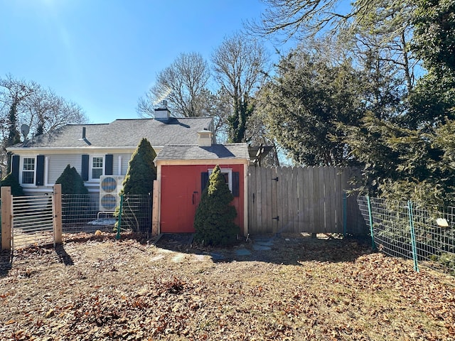 view of side of home with a chimney, fence, and an outdoor structure