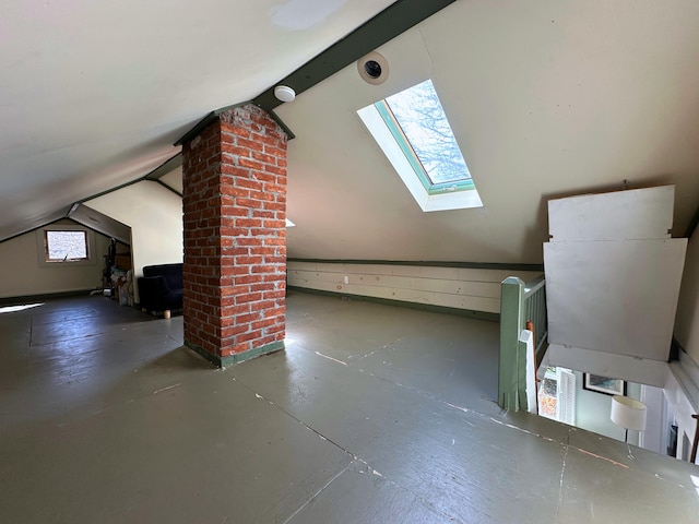 additional living space with lofted ceiling with skylight and concrete floors