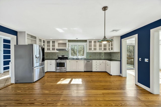 kitchen featuring open shelves, dark countertops, backsplash, appliances with stainless steel finishes, and under cabinet range hood