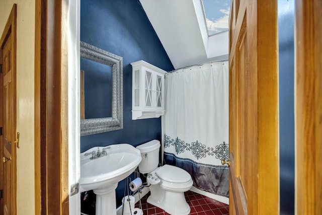 bathroom with vaulted ceiling with skylight, toilet, a shower with shower curtain, a sink, and tile patterned floors