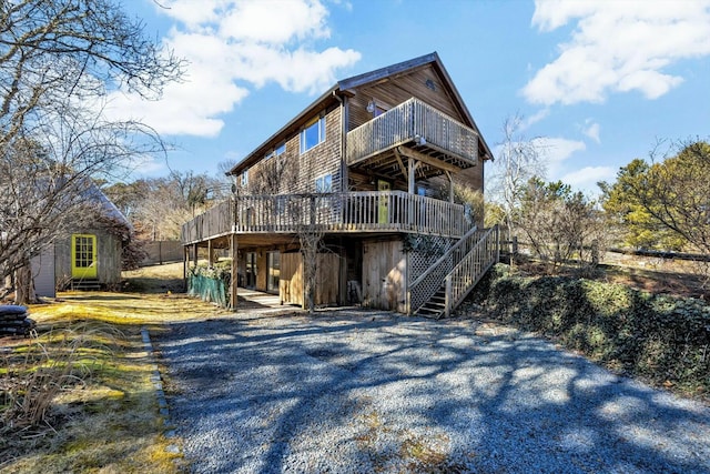 back of property featuring driveway, a deck, and stairs