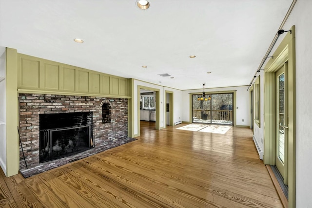 unfurnished living room with baseboards, light wood finished floors, a fireplace, and recessed lighting