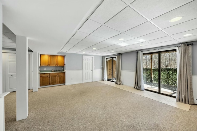 unfurnished living room featuring recessed lighting, wainscoting, light carpet, and a drop ceiling