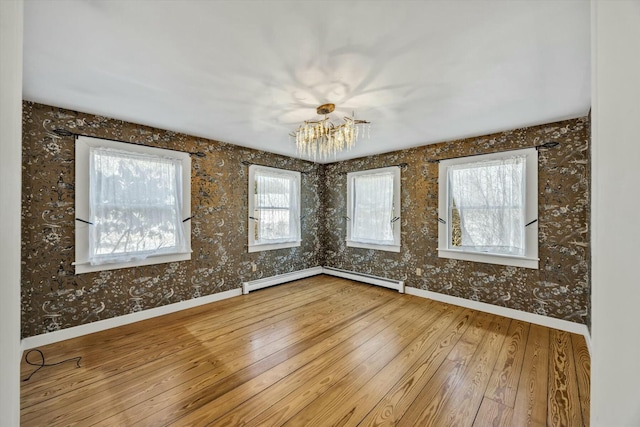 unfurnished room featuring a notable chandelier, a baseboard radiator, hardwood / wood-style flooring, and baseboards