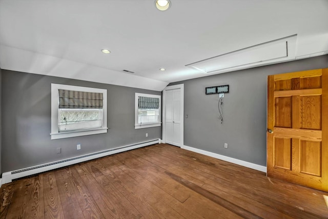 spare room with a baseboard heating unit, hardwood / wood-style floors, lofted ceiling, and baseboards