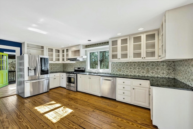 kitchen featuring open shelves, dark countertops, appliances with stainless steel finishes, dark wood-type flooring, and a sink