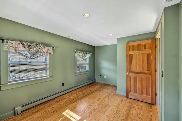 empty room featuring light wood finished floors, a baseboard radiator, recessed lighting, and baseboards