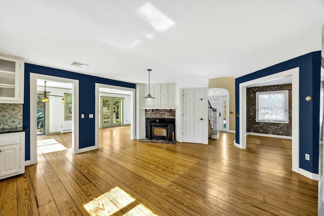 unfurnished living room featuring wood-type flooring, visible vents, a fireplace, and stairway