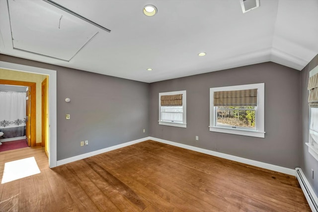 empty room featuring visible vents, a baseboard heating unit, attic access, wood finished floors, and baseboards