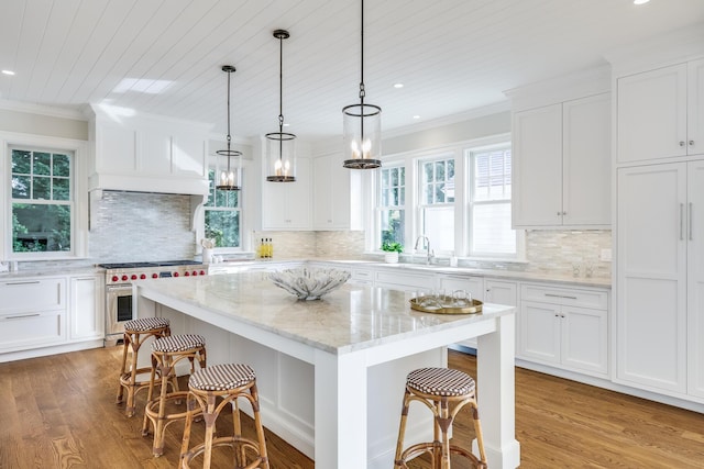 71 Towhee Ln, Orleans, MA 02653 - kitchen with a sink, high end stove, white cabinets, and a breakfast bar area