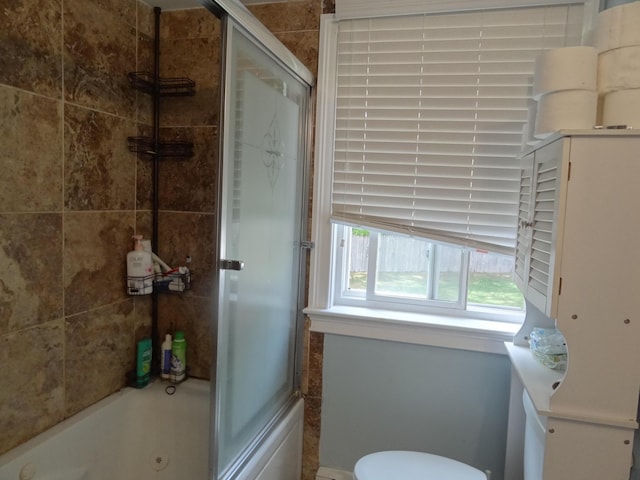 bathroom with shower / bath combination with glass door and toilet