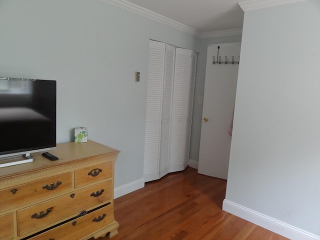 bedroom with a closet, ornamental molding, and dark hardwood / wood-style floors