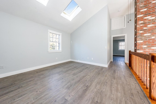 interior space featuring high vaulted ceiling, a skylight, baseboards, and wood finished floors