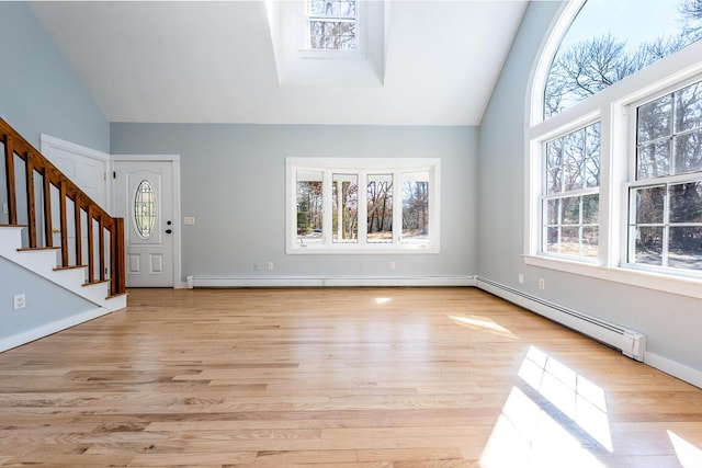 entryway with a baseboard heating unit, light wood-style floors, high vaulted ceiling, and stairs