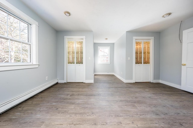 unfurnished bedroom with a baseboard heating unit, baseboards, and light wood finished floors