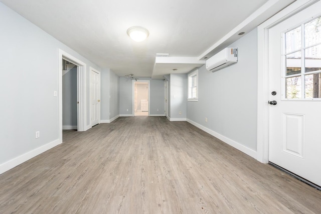 empty room with light wood-style floors, baseboards, and an AC wall unit