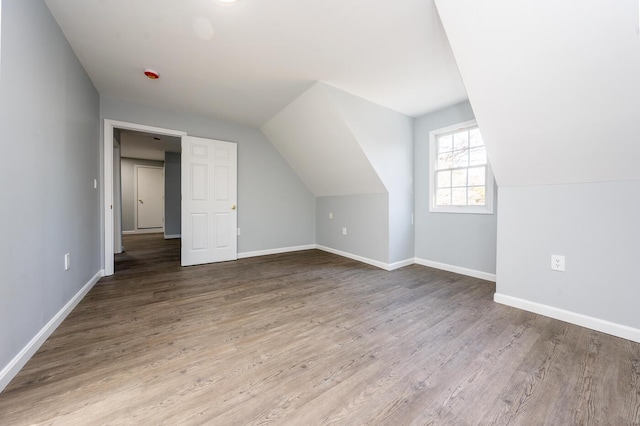 additional living space featuring baseboards and wood finished floors