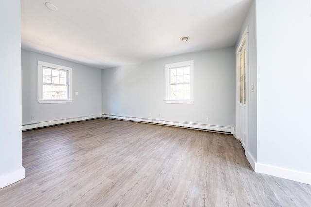 spare room with light wood finished floors, a baseboard radiator, and baseboards