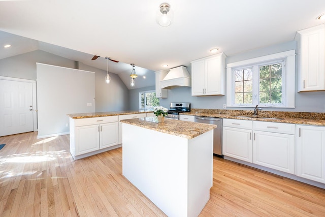 kitchen with white cabinets, custom range hood, appliances with stainless steel finishes, a center island, and pendant lighting