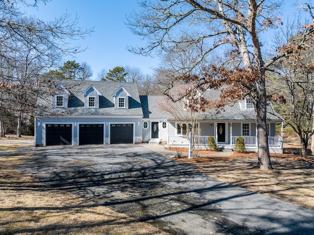 cape cod-style house featuring a garage, covered porch, and aphalt driveway