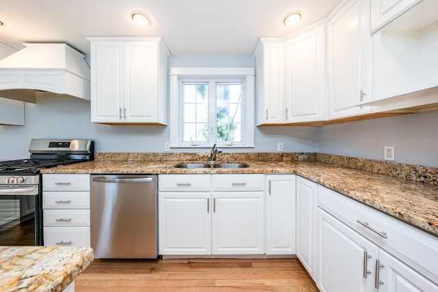 kitchen with appliances with stainless steel finishes, white cabinets, and a sink