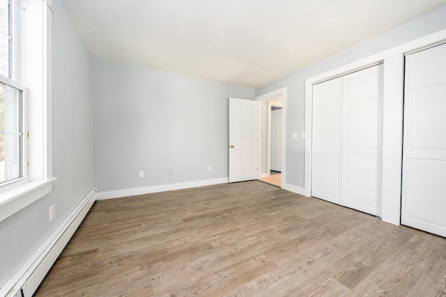 unfurnished bedroom featuring light wood-style floors, baseboards, and baseboard heating