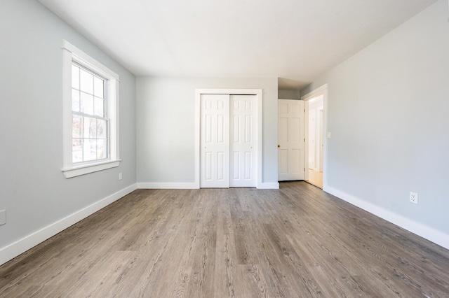 unfurnished bedroom with light wood-type flooring, baseboards, and a closet