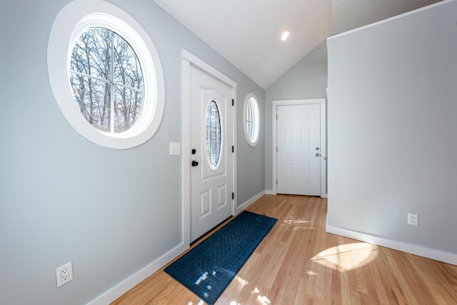 foyer entrance featuring vaulted ceiling, light wood-type flooring, a wealth of natural light, and baseboards