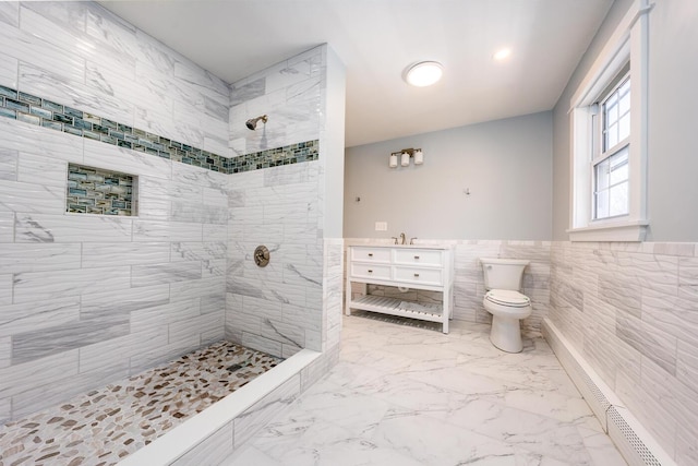 bathroom with toilet, marble finish floor, a tile shower, vanity, and tile walls