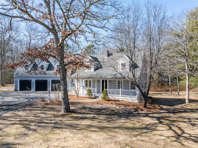 cape cod house featuring driveway, a chimney, and a porch