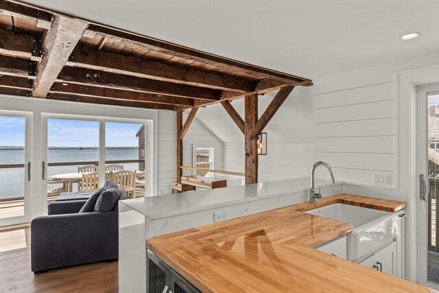 kitchen with wood-type flooring, wood walls, a healthy amount of sunlight, and a water view