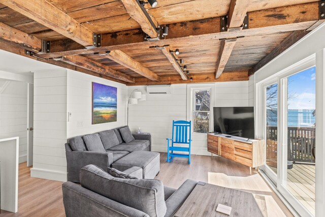 living room with beamed ceiling, wooden ceiling, a wall mounted AC, light wood-type flooring, and wood walls