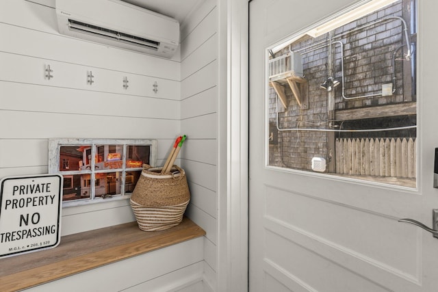 mudroom with a wall mounted air conditioner and wooden walls