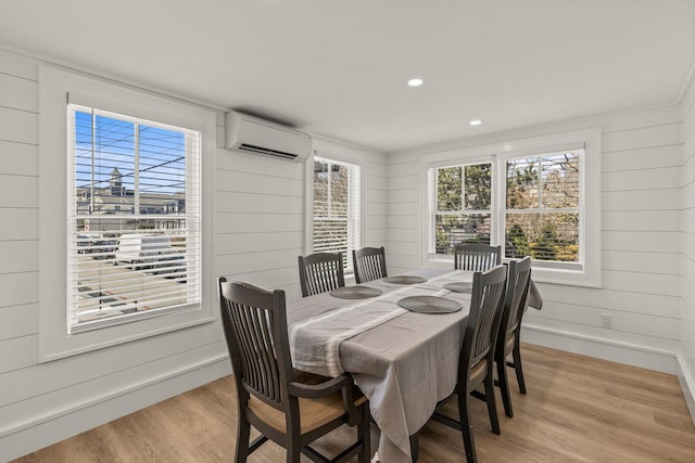 dining area with a wall mounted AC and light wood-type flooring