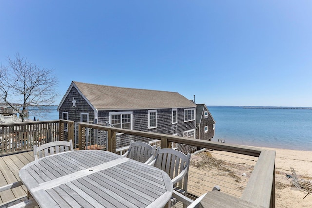 wooden deck featuring a beach view and a water view