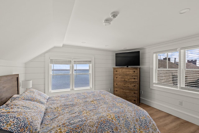 bedroom with wood-type flooring, wood walls, and vaulted ceiling