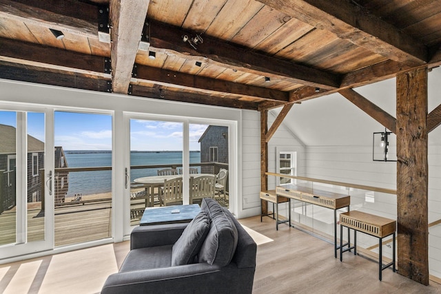 living room with vaulted ceiling with beams, light hardwood / wood-style floors, wood walls, a water view, and wooden ceiling