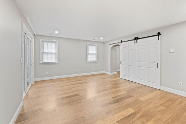49 Heather Ln, Centerville, MA 02632 - unfurnished bedroom featuring light wood-type flooring, baseboards, a barn door, visible vents, and arched walkways